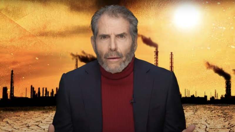 John Stossel stands in front of a factory | Stossel TV