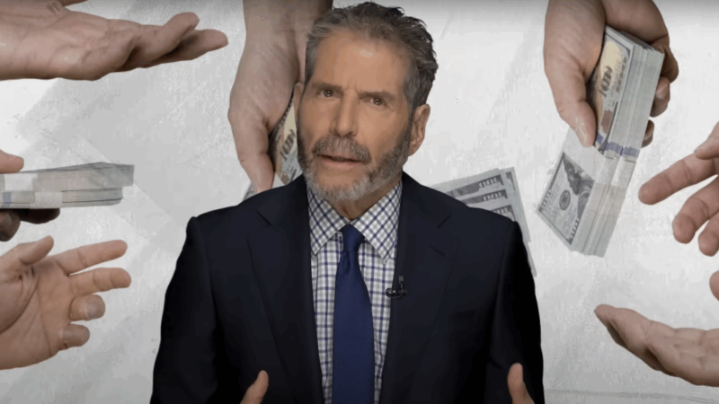 John Stossel stands in front of people holding wads of cash | Stossel TV