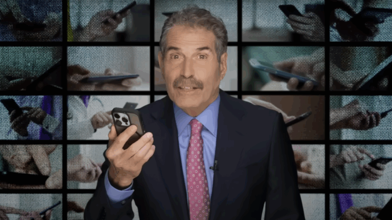 John Stossel holds a phone | Stossel TV