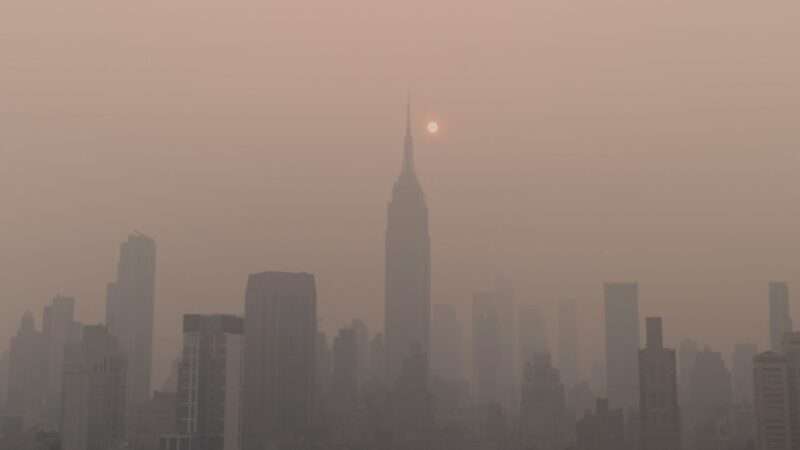 A photo captures the outline of the New York City skyline, but its obscured by a dark gray, slightly orange haze. The sun appears as a glowing orb next to the top of the Empire State Building. | Photo by <a href="https://unsplash.com/@ahmerkalam?utm_source=unsplash&utm_medium=referral&utm_content=creditCopyText">Ahmer Kalam</a> on <a href="https://unsplash.com/photos/a-foggy-city-skyline-with-the-sun-in-the-distance-Reuk1nmutFI?utm_source=unsplash&utm_medium=referral&utm_content=creditCopyText">Unsplash</a>