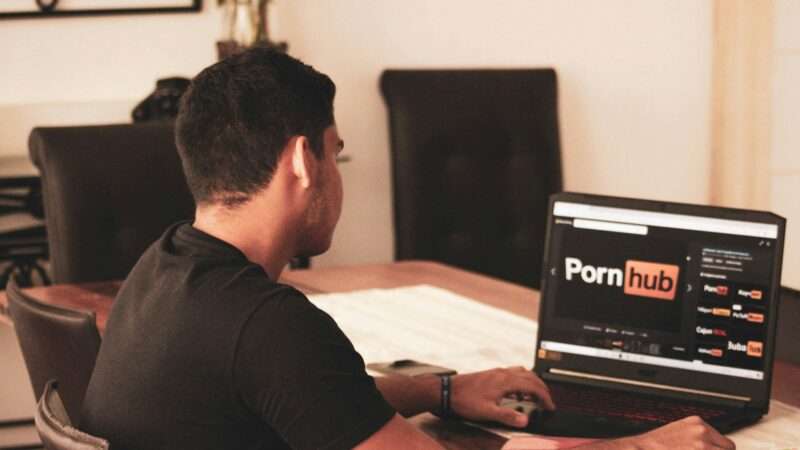 A man on the Pornhub website on his laptop | Photo by <a href="https://unsplash.com/@dreamyframing?utm_source=unsplash&utm_medium=referral&utm_content=creditCopyText">franco alva</a> on <a href="https://unsplash.com/photos/man-in-black-t-shirt-using-black-laptop-computer-aqFzxyC3rf8?utm_source=unsplash&utm_medium=referral&utm_content=creditCopyText">Unsplash</a>       