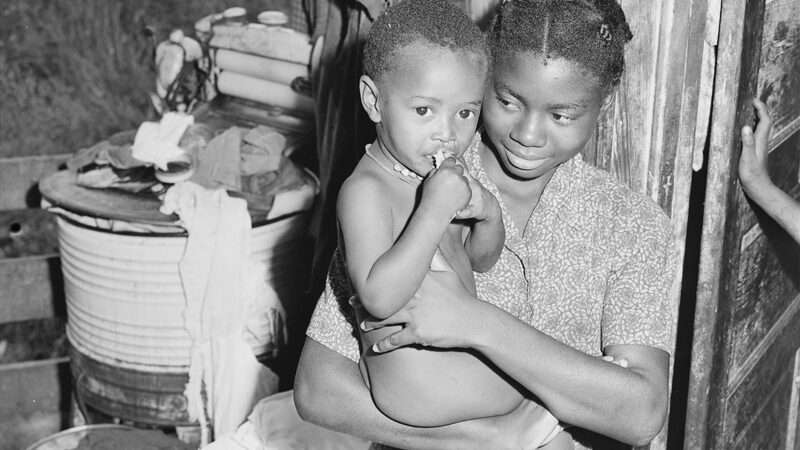 A black and white photo of a woman holding a small child | Photo: Power & Light/National Archives