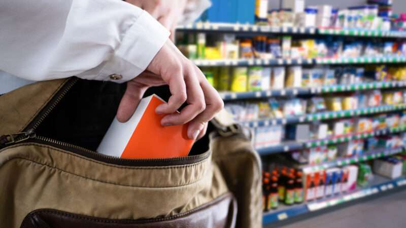 A woman shoplifts from a grocery store, stuffing an item into her purse. | Andrey Popov | Dreamstime.com