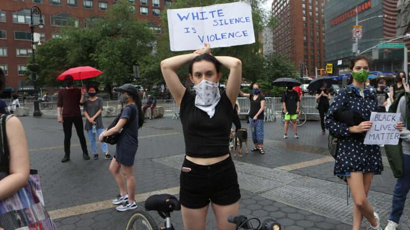 A woman holds a protest sign that says "white silence is violence" | Krista Kennell/ZUMA Press/Newscom