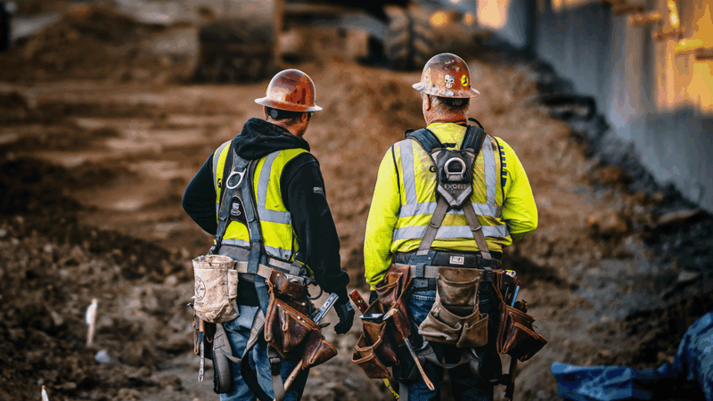 Two workers wearing construction equipment standing in front of an empty dirt area. | Photo: Daniel Mekis