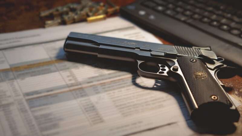 A semiautomatic handgun and some papers on a desk. | Illustration: Midjourney