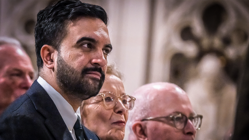 Zohran Mamdani photographed from a diagonal angle, with a woman and a man next to him. | Laura Brett/ZUMAPRESS/Newscom