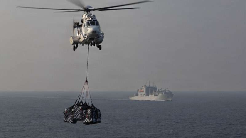 A Eurocopter AS565 Panther helicopter transports cargo to the flight deck of Nimitz-class aircraft carrier USS Abraham Lincoln (CVN 72) during a replenishment-at-sea with Lewis and Clark-class dry cargo ship USNS Carl Brashear (T-AKE-7) in support of Operation Epic Fury, March 18, 2026. | U.S. Navy