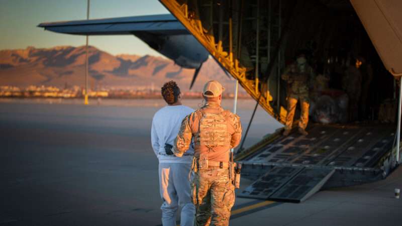 Government official leading a detained immigrant onto a Camp East Montana plane | Polaris/Newscom