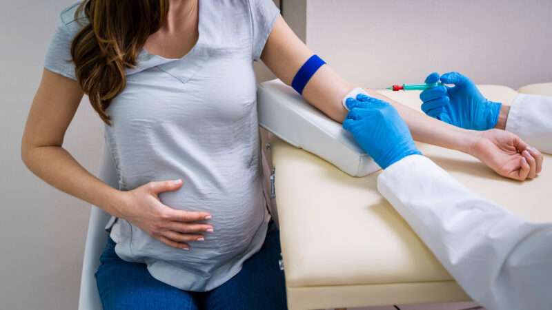 A doctor preps a pregnant person's arm for a blood draw | Photo: AndreyPopov/Newscom