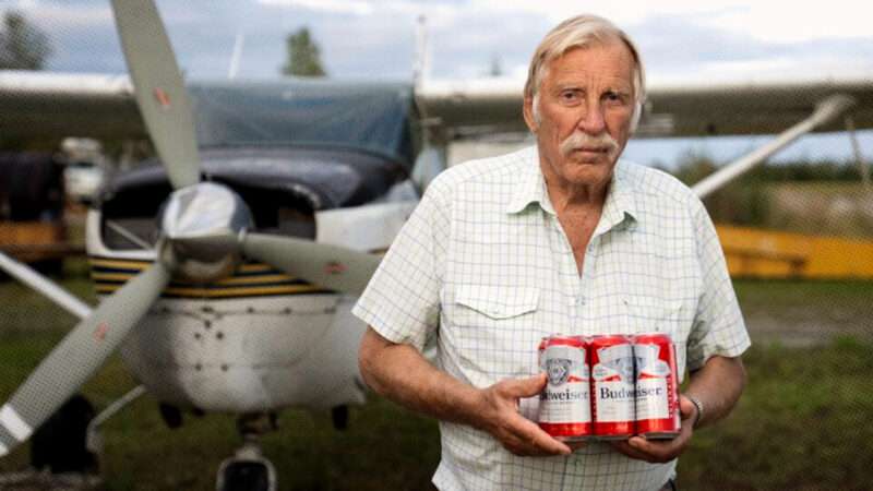 Ken Jouppi holds a six-pack of beer while standing in front of his airplane | Institute for Justice