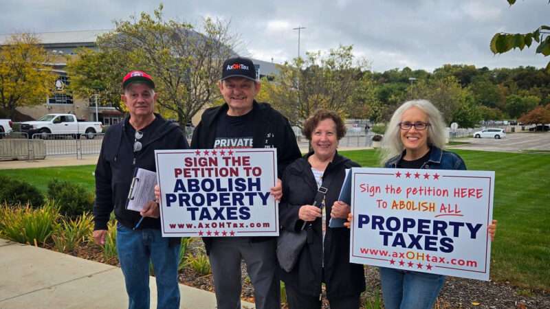 Four elderly protesters hold two signs that say "Sign the petition to abolish property taxes." | Denise DiFabio/Facebook