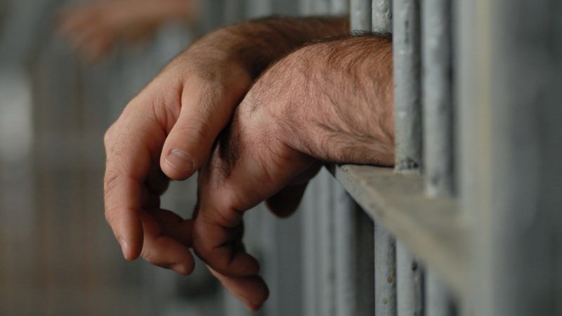 hands hanging out of a prison cell