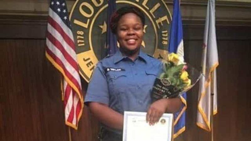 Breonna Taylor in her EMT outfit, in front of Louisville city logo | family photo