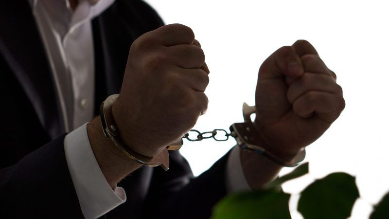 dreamstime_xl_103769504 | Photo <a href="https://www.dreamstime.com/financial-fraud-concept-businessman-politician-man-financial-fraud-concept-businessman-politician-man-suit-handcuffs-image103769504">103769504</a> © <a href="https://www.dreamstime.com/terovesalainen_info" itemprop="author">Tero Vesalainen</a> - <a href="https://www.dreamstime.com/photos-images/treason-handcuffs.html">Dreamstime.com</a>