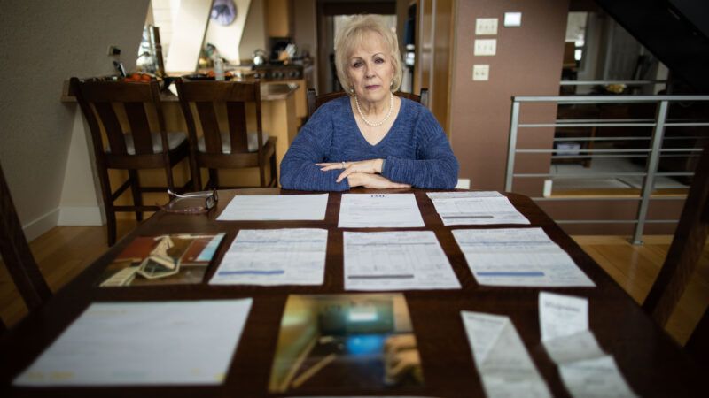 Vicki Baker seated at her table in front of a mix of evidence and court documents from her time in court after a SWAT team destroyed her home