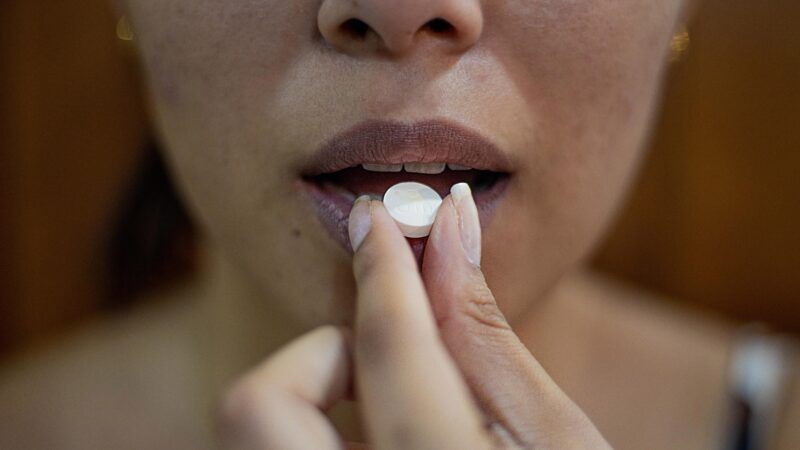 close up of a woman putting a pill in her mouth