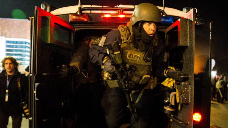 Policeman in SWAT gear getting out of the back of a police vehicle. | Ting Shen/Sipa USA/Newscom