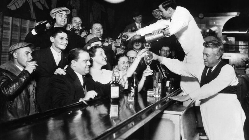 Black and white photo of a crowd at a bar in the early 1900s