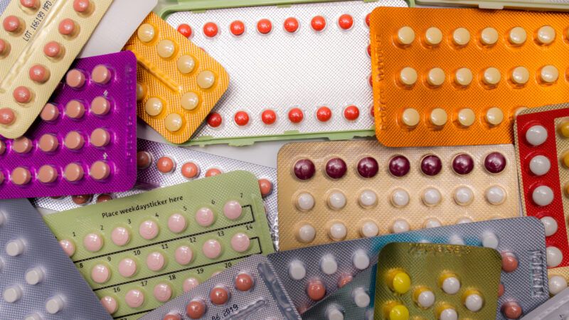 Around a dozen colorful birth control pill packs arranged on top of each other.