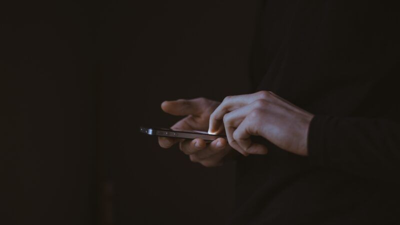 hands on dark background flipping through cellphone | Photo by <a href="https://unsplash.com/@gilleslambert?utm_source=unsplash&utm_medium=referral&utm_content=creditCopyText">Gilles Lambert</a> on <a href="https://unsplash.com/?utm_source=unsplash&utm_medium=referral&utm_content=creditCopyText">Unsplash</a>   