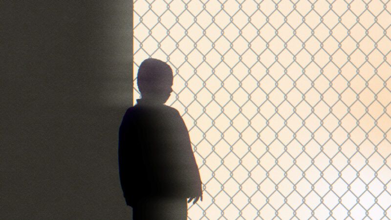 Silhouette of a child behind a chain link fence