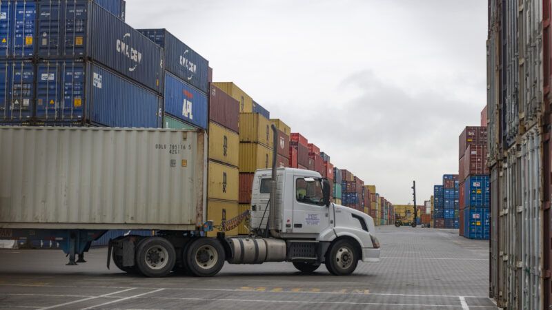 A sixteen-wheel truck driving in front of containers at a port | Yichuan Cao/Sipa USA/Newscom