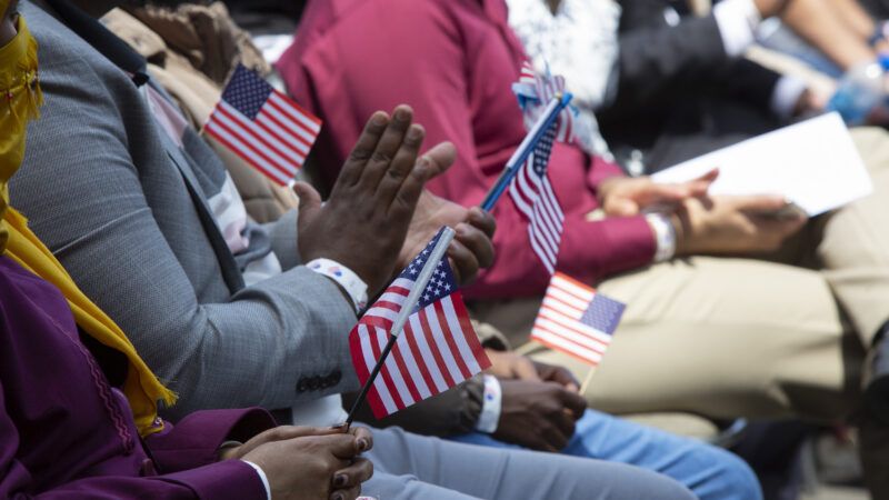 Naturalized Americans holding American flags at a ceremony