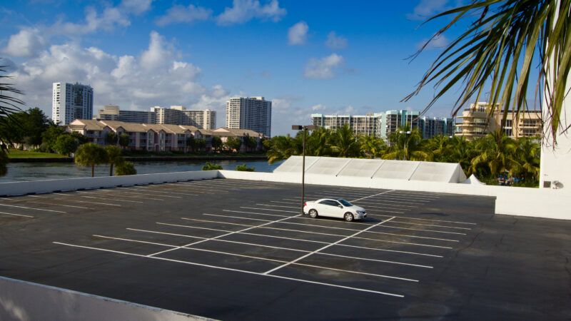 high perspective shot of a parking lot with a single white car in it and a skyline in the background