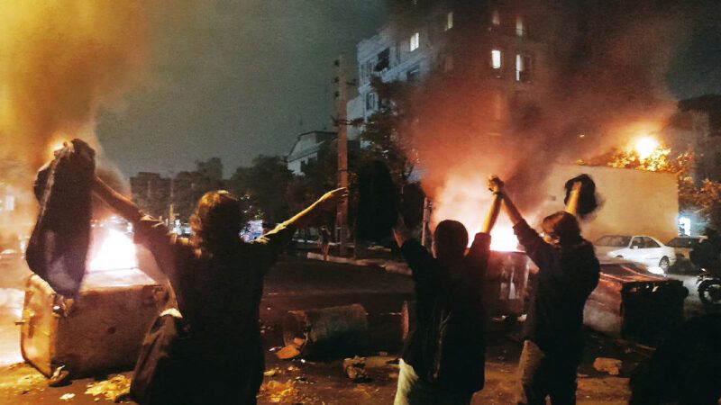 Iranian women without hijabs stand in the street around a fire in protest | Abaca Press/SalamPix/Abaca/Sipa USA/Newscom