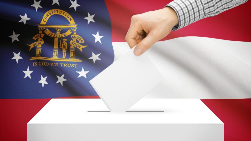 A hand casting a ballot in front of the Georgia state flag. | DPST/Newscom