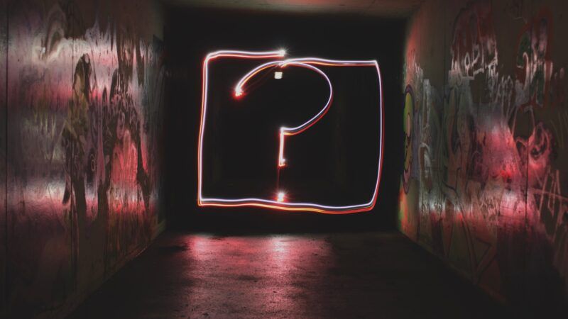 neon question mark surrounded by graffiiti