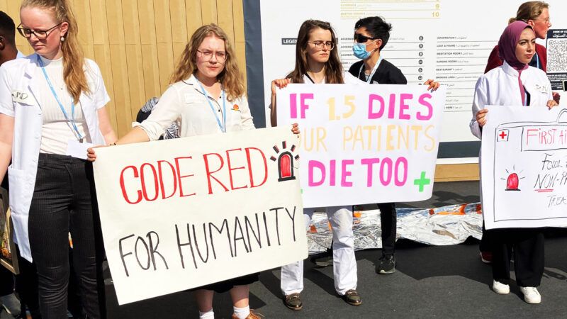 Climate change activists hold up signs about rising temperatures at COP27