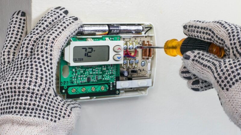 Thermostat being repaired | Larry Hazelet / Dreamstime.com