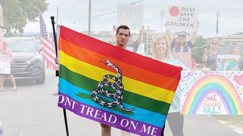 Chase Oliver, Georgia's Libertarian U.S. Senate candidate, holding a flag that combines Don't Tread On Me with pride | Photo by Eric Boehm, illustration by Lex Villena