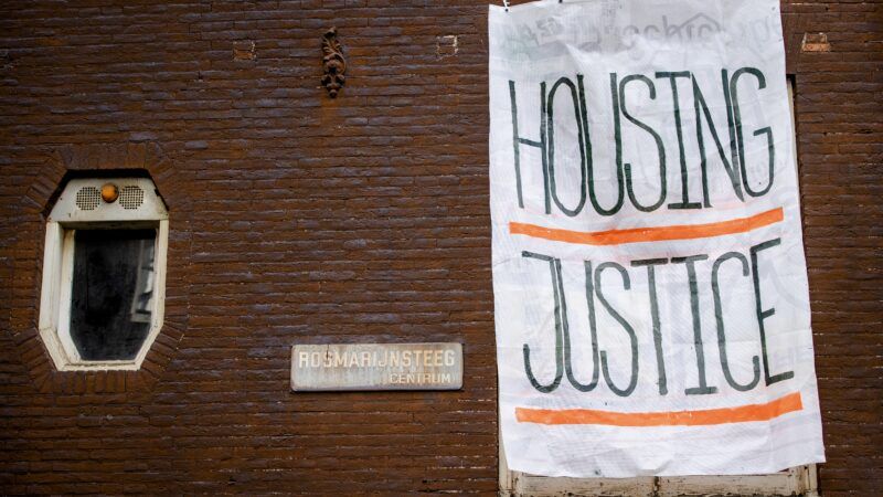 a housing justice sign hangs on a building