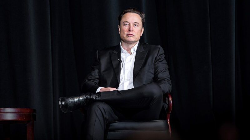 Elon Musk sits in a chair against a dark background | U.S. Air Force photo by Trevor cokley