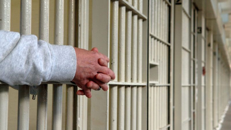 hands reaching out from behind prison bars