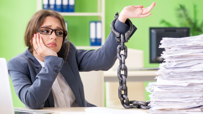 Woman chained to paperwork at her desk | Photo 124018271 © Elnur | Dreamstime.com