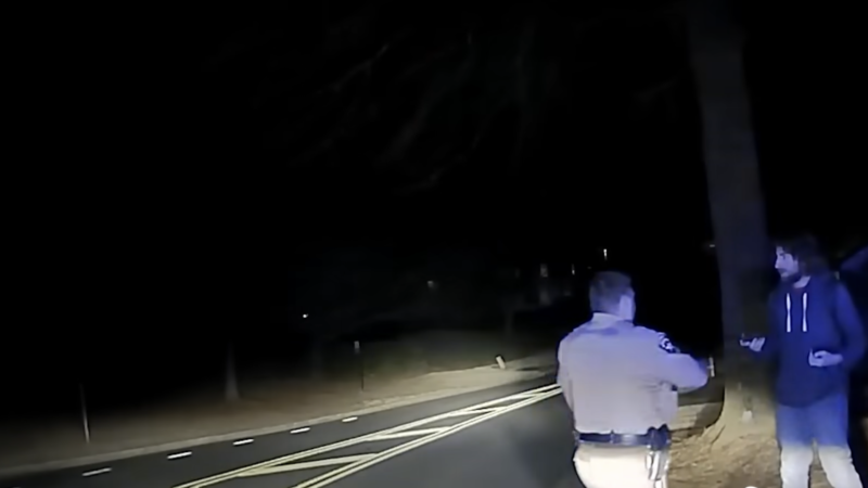 A screenshot of dash camera footage in which a sheriff's deputy approaches a bewildered pedestrian in the middle of the night.