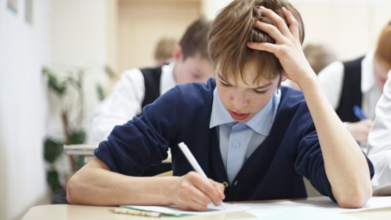 A male student struggles while taking a test.