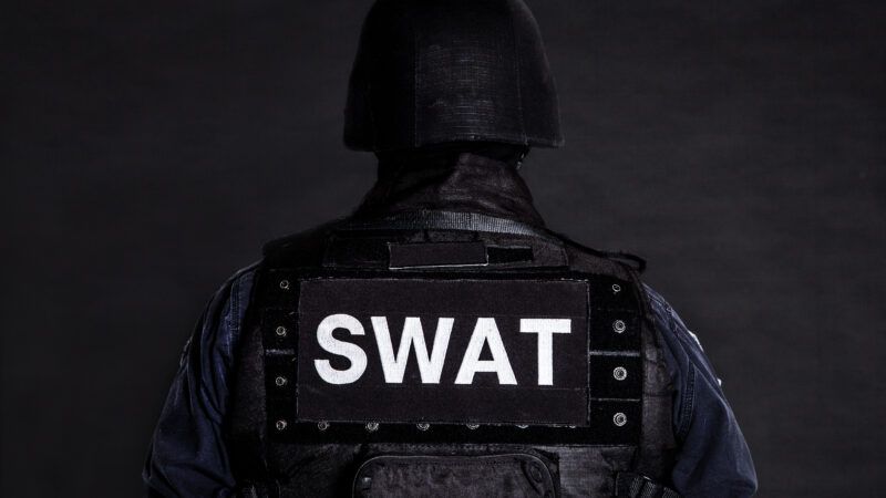 A SWAT officer faces away from the camera against a dark gray background. | Photo 38227168 © Oleg Zabielin | Dreamstime.com