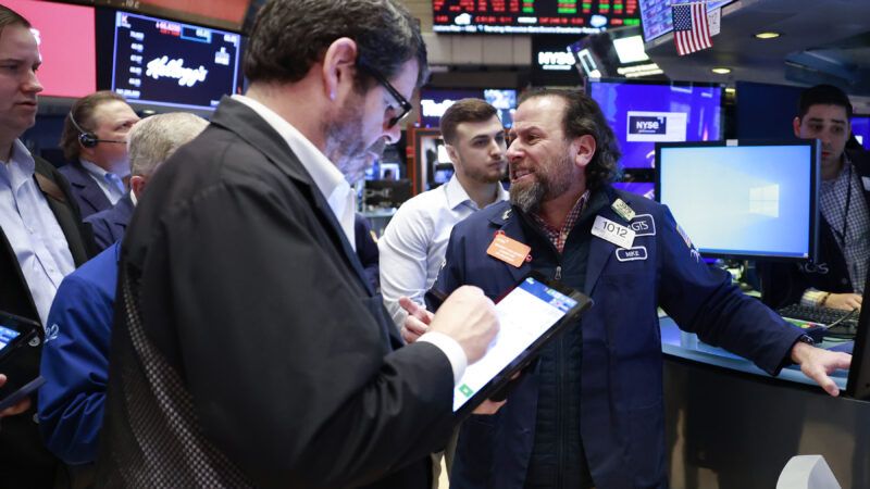 A group of Wall Street traders huddle around a desk at the New York Stock Exchange.