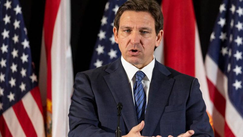 Ron DeSantis speaks in front of a row of American and state of Florida flags