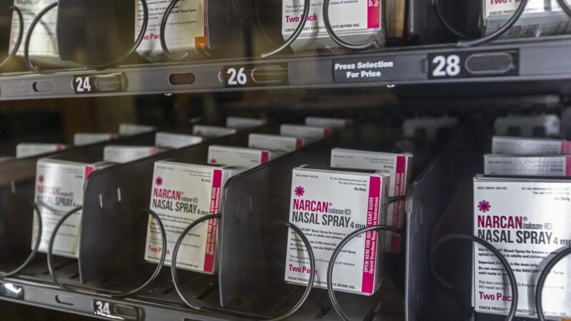 Boxes of Narcan naloxone spray behind glass in a vending machine.