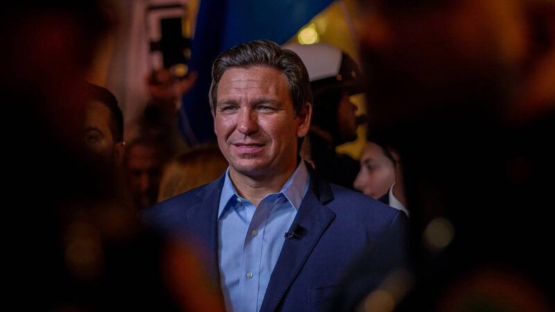 Ron DeSantis in a blue suit and blue shirt among a crowd.