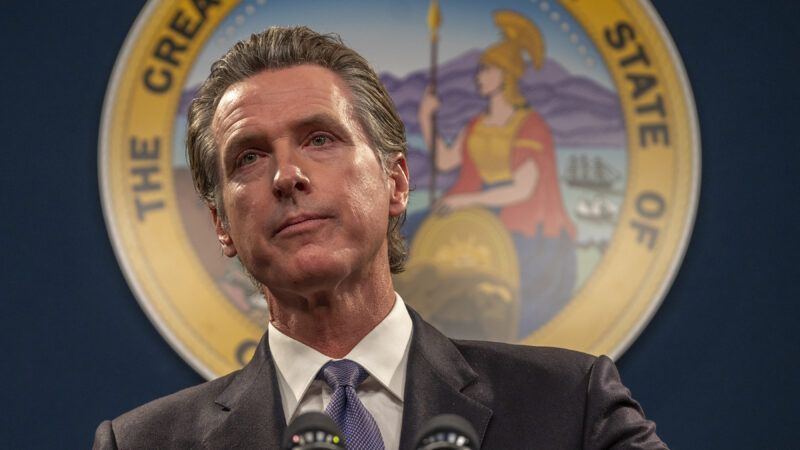 California Gov. Gavin Newsom at a microphone in front of the seal of California