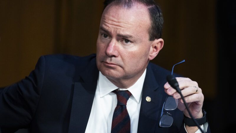 Sen. Mike Lee (R–Utah) at a Senate Judiciary committee meeting. He is holding his glasses in one hand and looking off to the side.