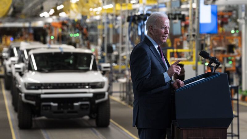 President Joe Biden speaks in front of a lectern inside an automobile factory, with a line of Hummer EVs in the background. | Dominick Sokotoff/Sipa USA/Newscom