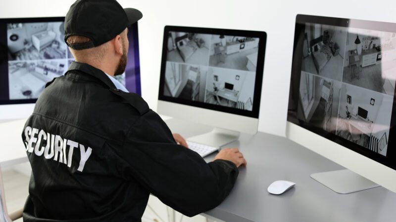 A security guard sits, monitoring home surveillance footage. | Chernetskaya | Dreamstime.com